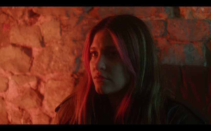 Still: a woman lit in red