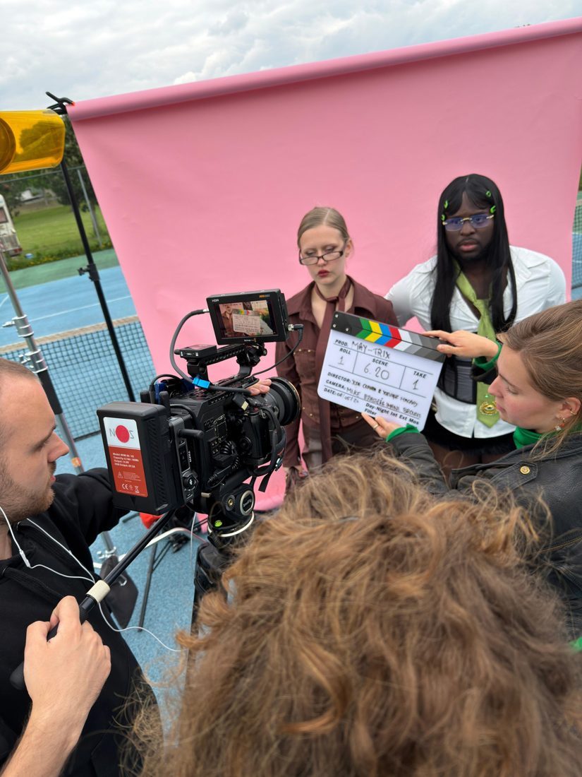 Crew filming in front of the pink backdrop